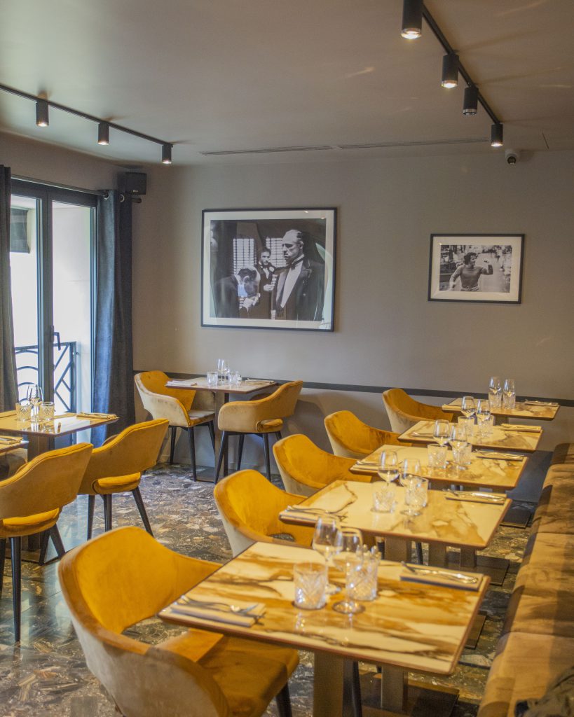 Salle du ristorante de Levallois avec fauteuils en velours ocre et photographies noir et blanc.